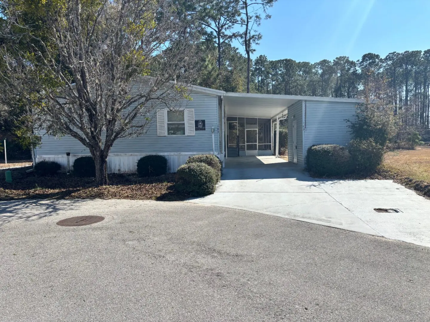 Small white building with driveway and trees.