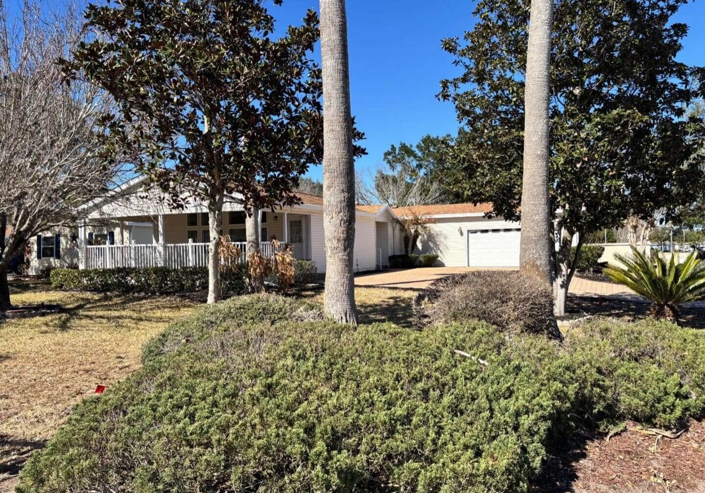 House with garden and driveway under trees.